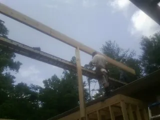 Carpenter setting a ridge beam over a new addition frame — Ice Dam Removal by Roofing Brothers in Tribune
