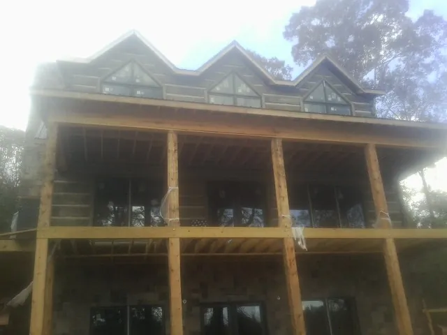 Dormers and porch framing on a large log home under construction — Roof Coating work by our crew in Tribune