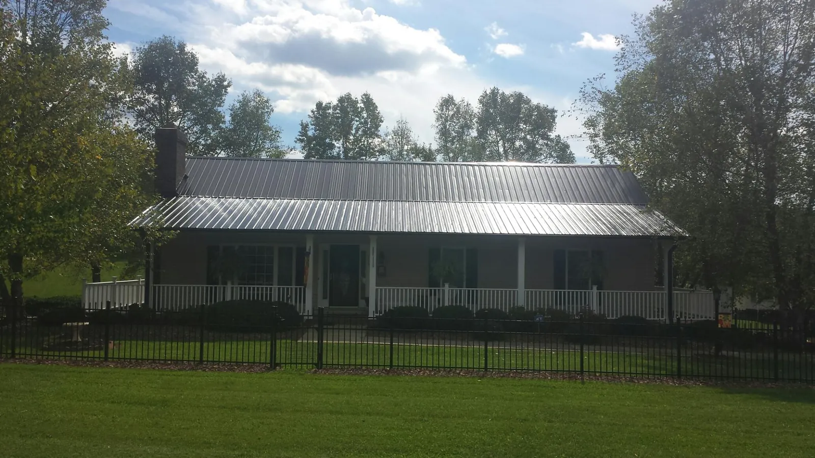 Gray metal roof on a brick ranch with a full width front porch — Gutter Guard Installation work by our crew in Tribune