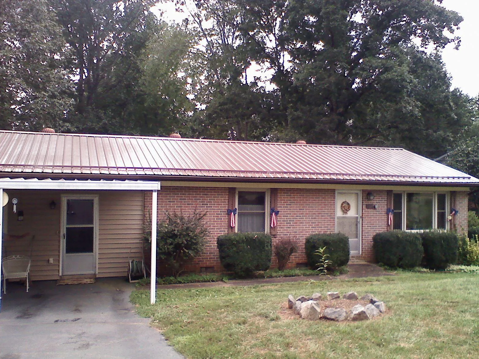 Bronze metal roof and carport on a brick ranch home — Roof Repair work by our crew in Tribune