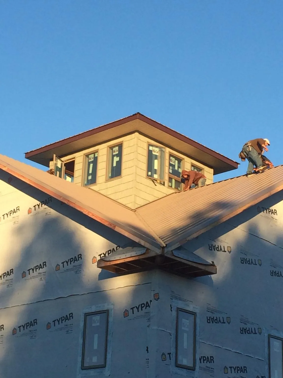 Roofers working around a rooftop cupola on a new metal roof at sunset — Roof Waterproofing in Tribune by Roofing Brothers